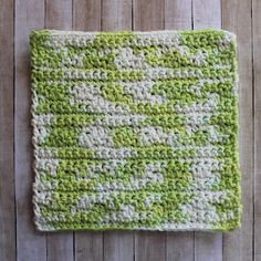 a green and white crocheted dishcloth sitting on top of a wooden table