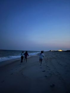 three people walking on the beach at night