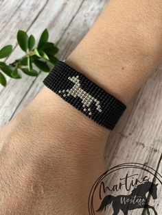 a woman's arm with a black and white horse beaded bracelet on it