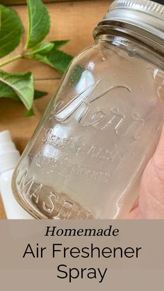 a hand holding a mason jar filled with air freshener spray