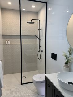 a bathroom with a toilet, sink and shower in it's stall area next to a large mirror