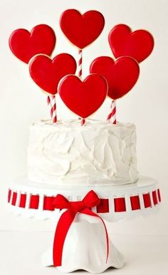 a white cake topped with lots of red hearts