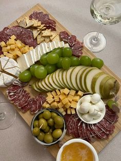 an assortment of cheeses, olives, and meats on a cutting board