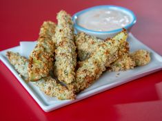 some fried food on a white plate with dipping sauce