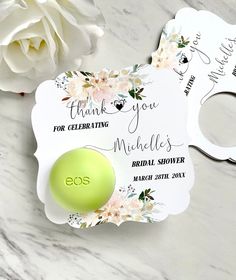 the wedding thank card is next to a white rose and a green ball on a table