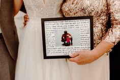 a man and woman holding up a framed photo with words written on it in front of them