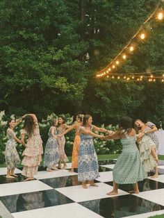 a group of women standing on top of a checkered floor in front of trees