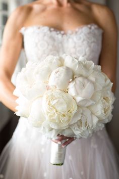 a bride holding a bouquet of white flowers