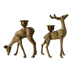 two brass deer candlesticks are standing next to each other