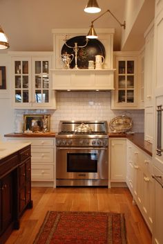 a kitchen with white cabinets and stainless steel stove top oven in the center, along with an area rug on the floor