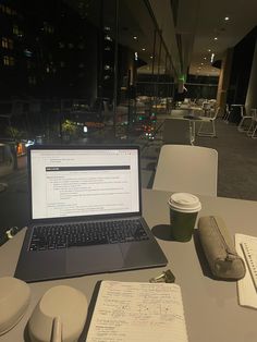 an open laptop computer sitting on top of a table next to a cup of coffee