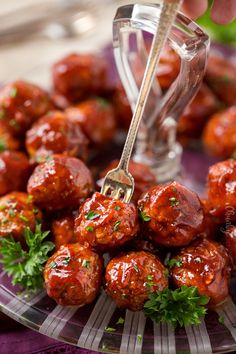 a plate full of meatballs and garnish being drizzled with sauce