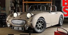 an old style sports car is parked in a garage next to a red sign that says bss