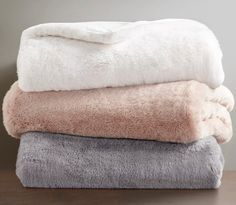 three towels stacked on top of each other in different colors and sizes, with one folded up