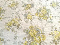 a yellow and blue flowered bedspread on a bed with white linens