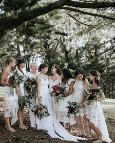 a group of women standing next to each other in front of a tree filled forest