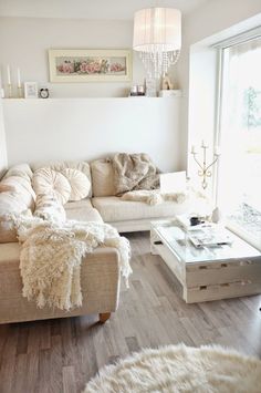 a living room filled with white furniture and lots of pillows on top of it's couches