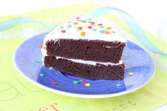 a slice of chocolate cake with white frosting and sprinkles on a blue plate