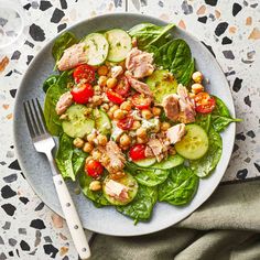 a salad with cucumbers, tomatoes and chickpeas is on a plate