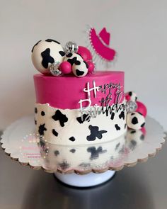 a birthday cake decorated with black and white polka dots, pink ribbon, and silver decorations