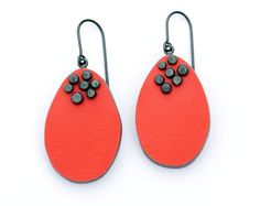 two pairs of earrings with black and red designs on the front, one is shaped like a tear