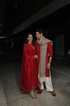 a man and woman standing next to each other in front of a dark room with lights on