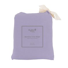 the bamboo crib sheet in lavender is folded and has a white ribbon on it