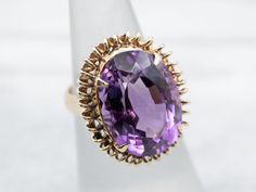 This ring is truly gorgeous! A large and beautiful deep purple amethyst sits in the center, with an amazing cut and vibrant purple color that flickers with bright pops of violet! The stone is expertly cut to really display the stone’s color and sparkle! The looping yellow gold mounting and simple prongs are all this stone needs to frame it to perfection!Metal: 10K Yellow Gold Gem: Amethyst 11.30 CaratsGem Measurements: 17.2 x 12.6 mm, OvalRing Size: 5Marks: “10K” Stamped on the inside band Elegant Purple Amethyst Ring With Large Stone, Amethyst Cocktail Ring, Garnet And Diamond Ring, Engagement Ring Diamond Cut, Tanzanite Ring, Diamond Cocktail Rings, Amethyst Jewelry, Diamonds And Gold, Blue Zircon