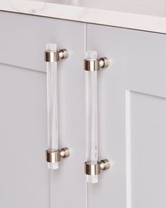 two glass handles on the front of a white cabinet