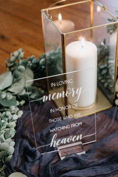 a candle is sitting on top of a table with greenery and candles in it