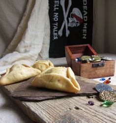 some food is laying out on a wooden board next to a pirate flag and trinkets