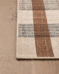 a brown and white checkered rug on top of a wooden floor