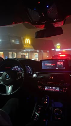 the interior of a car at night with mcdonald's lit up in the background