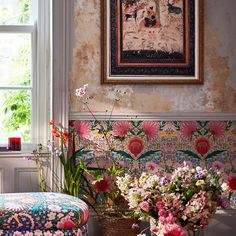 a room filled with lots of flowers next to a painting on the side of a wall