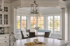 a kitchen with white cabinets and an island in front of two windows that have glass panes on them