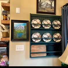 a shelf with plates and other items on it next to a lamp in a room