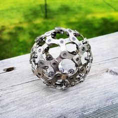 a bike chain ball sitting on top of a wooden table next to a green field