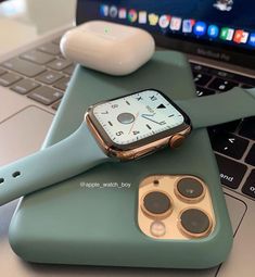 an apple watch sitting on top of a green phone case next to a laptop computer