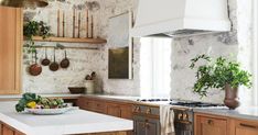 a kitchen with wooden cabinets and white counter tops, an island in the middle is surrounded by potted plants