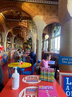 people sitting at tables in a restaurant with red tablecloths and colorful decorations on the walls