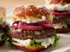 three hamburgers with onions, lettuce and cheese