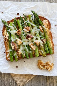 a piece of bread with asparagus and walnuts on it