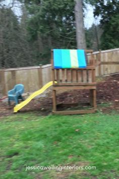 a wooden bench sitting in the middle of a yard next to a slide and tree