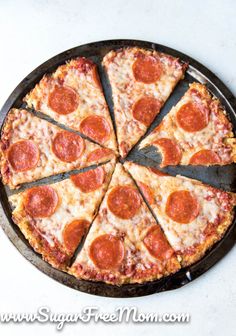 a pepperoni pizza cut into eight slices on a black pan with a spatula