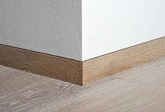 the corner of a room with white walls and wood flooring on top of it