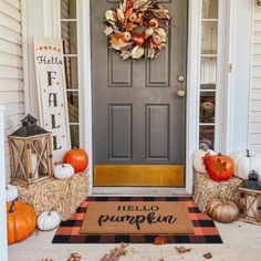 a front door decorated for fall with pumpkins and hay bales