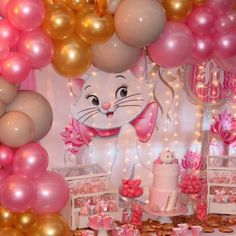 a cat themed birthday party with pink and gold balloons on the wall, cake and dessert table