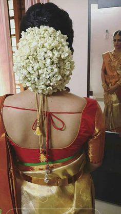 the back of a woman's head with flowers in her hair and dress on