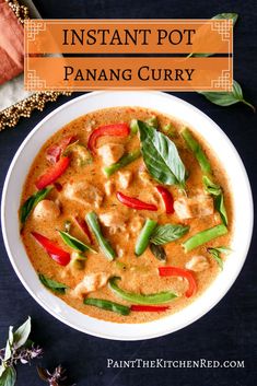 a white bowl filled with red curry and green peppers on top of a black table