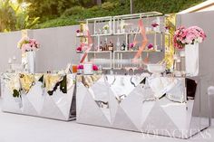 an outdoor bar decorated with pink flowers and gold foil for a wedding or bridal party